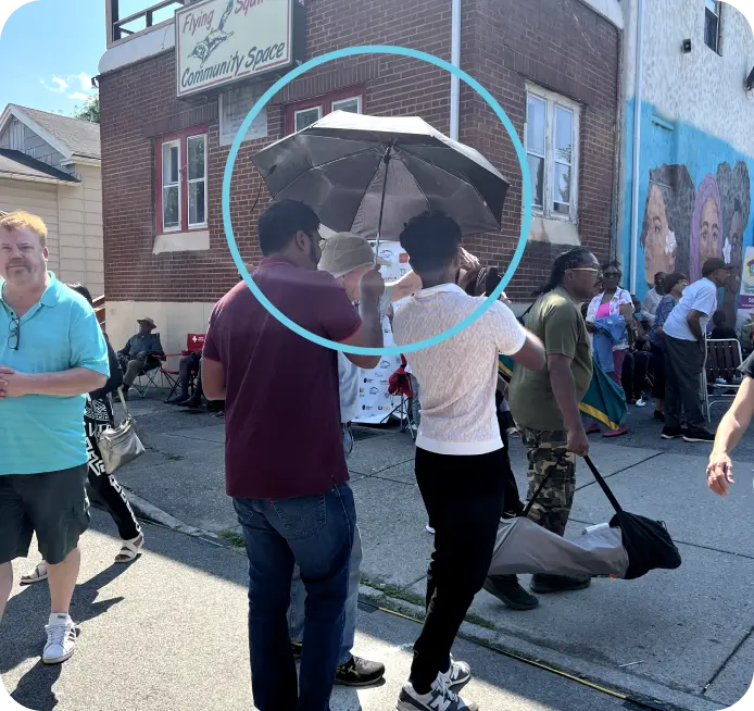 Participants using umbrella to shield phone from sunlight during AR demo